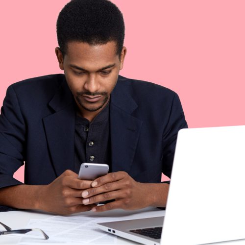 Image of a person using a phone and a laptop